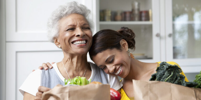 Mother and daughter unpacking groceries in kitchen