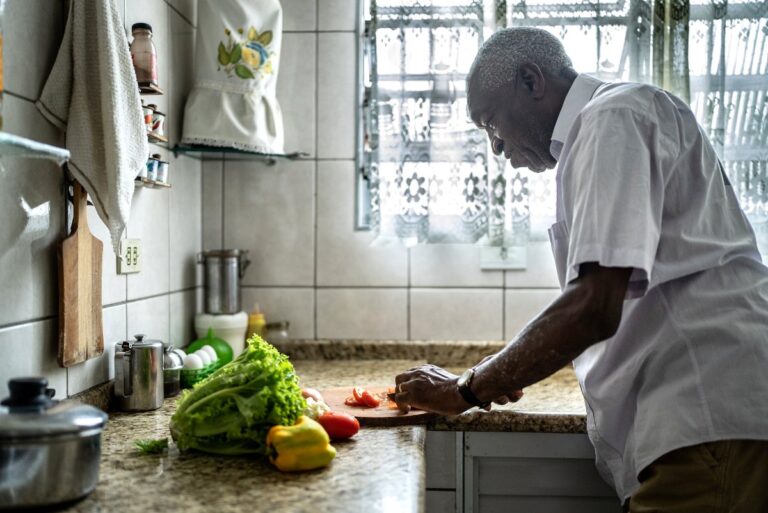 Senior man cutting tomatoes in the kitchen