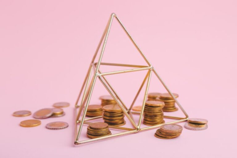 A golden pyramid structure behind a plain background with money in and around it.