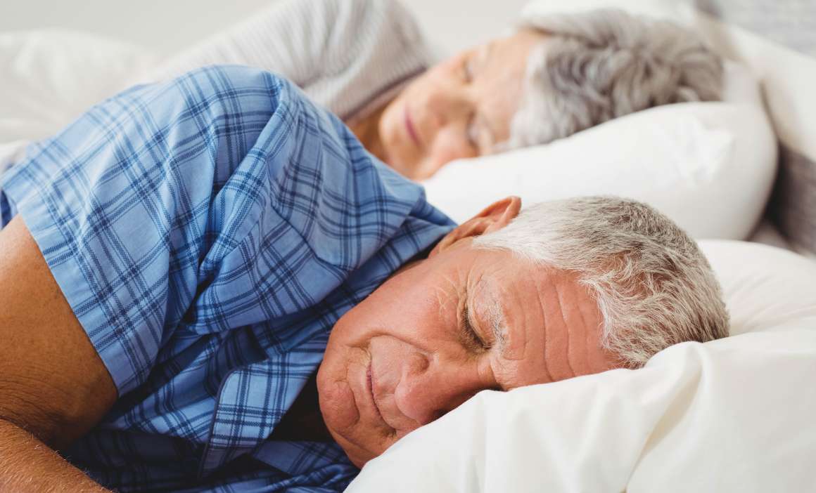 Senior couple sleeping on bed in bedroom