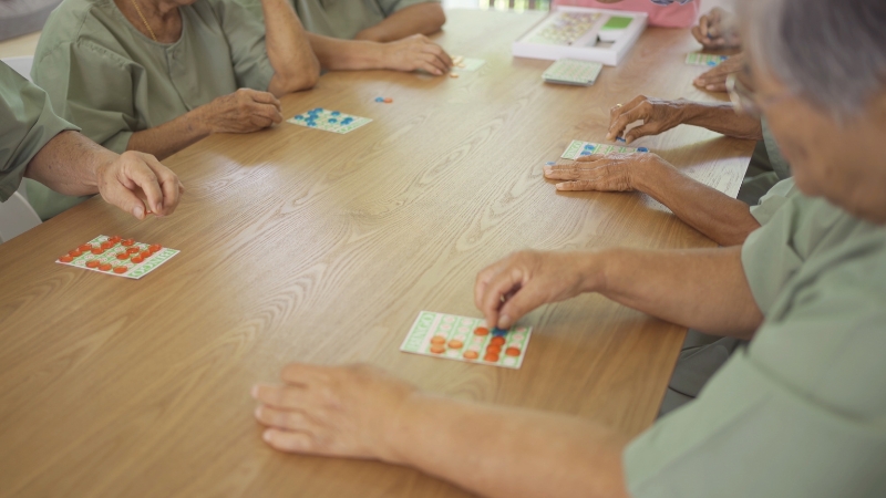 Older adults play a tabletop game together and focus on placing pieces on their boards