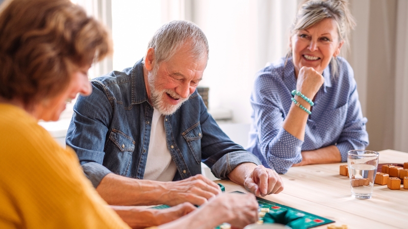 Seniors enjoy trivia games together at a table while laughing and staying mentally active