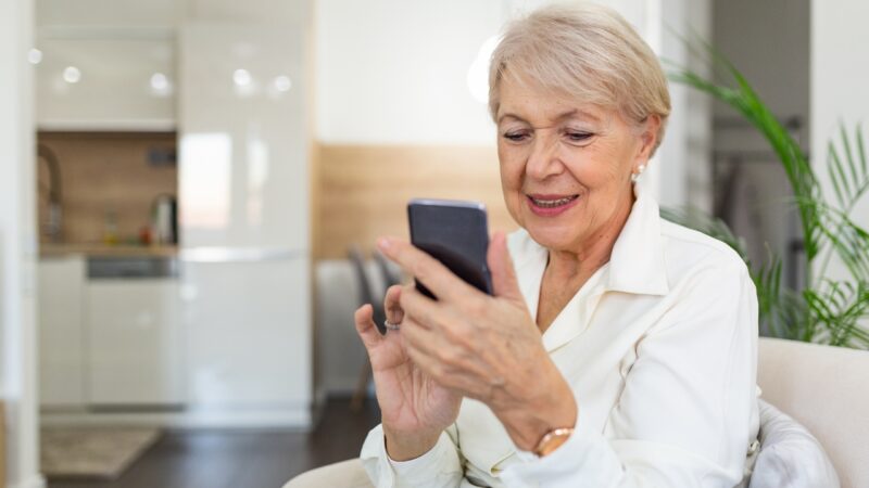 Older woman at home taking a photo with her smartphone