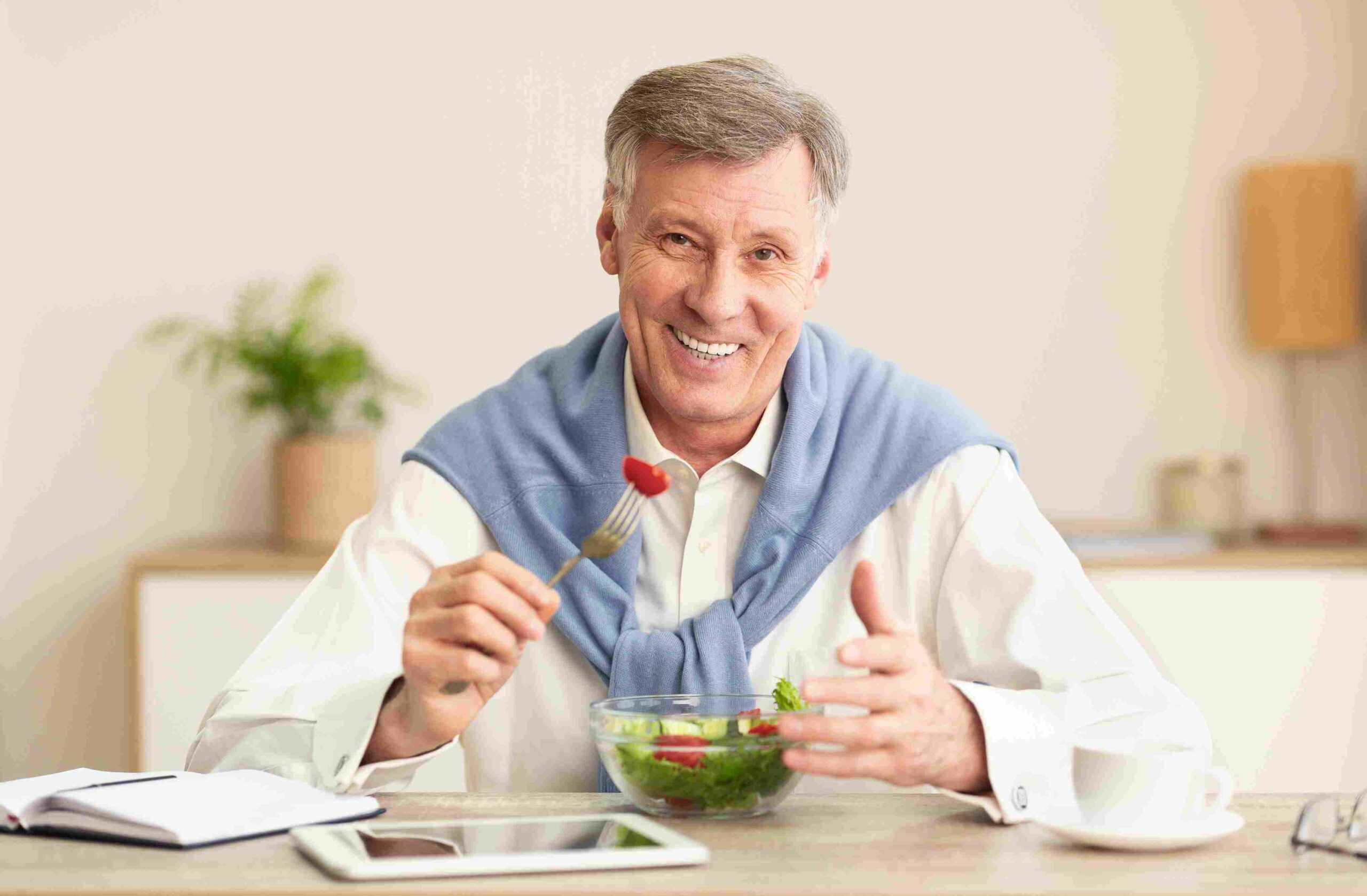 Smiling senior man eating a healthy salad at home