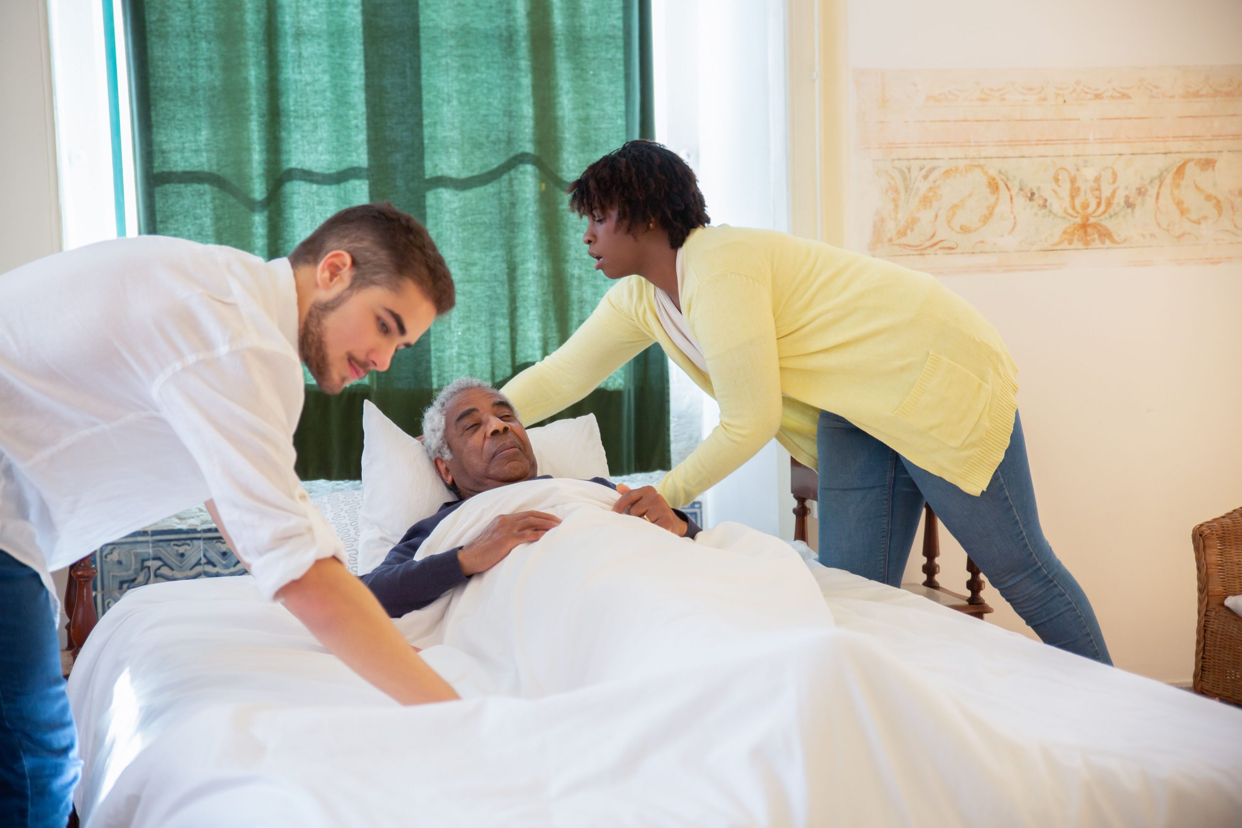 Caregiver providing bedside assistance to an older man at home