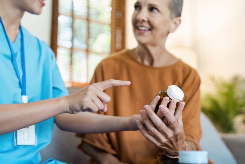 Caring Nurse Assisting Senior Woman with Medication at Home - Healthcare Home Concept