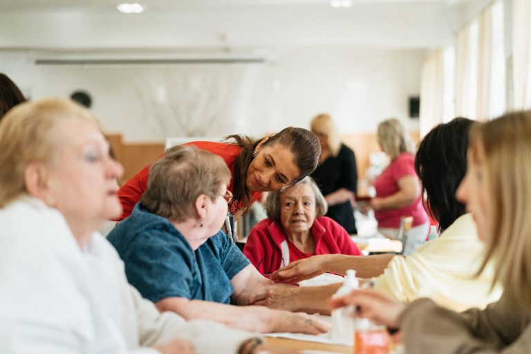 Older adults share a table activity with caregivers at a community day program.