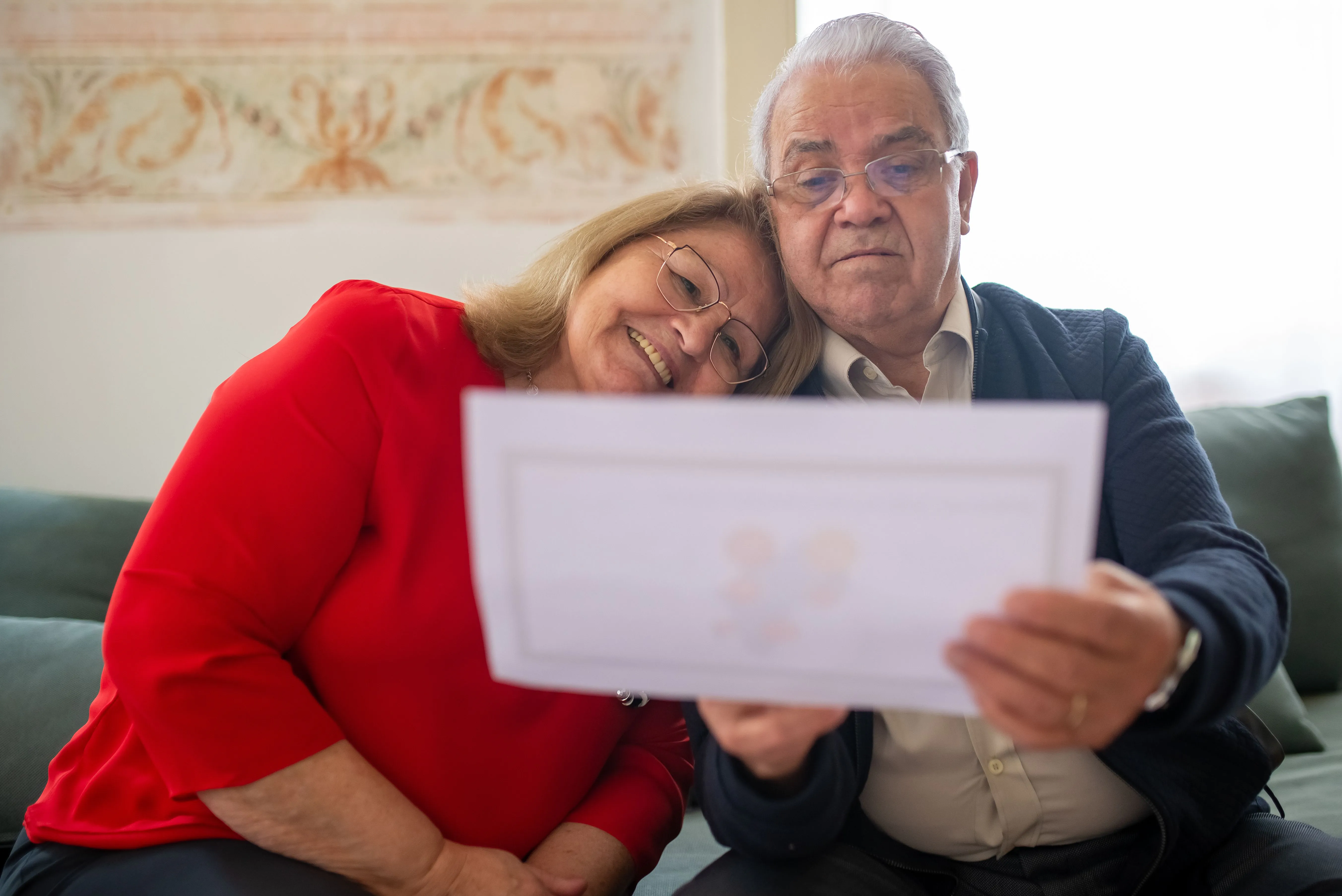 Senior couple reviewing a document together at home while considering health coverage choices.