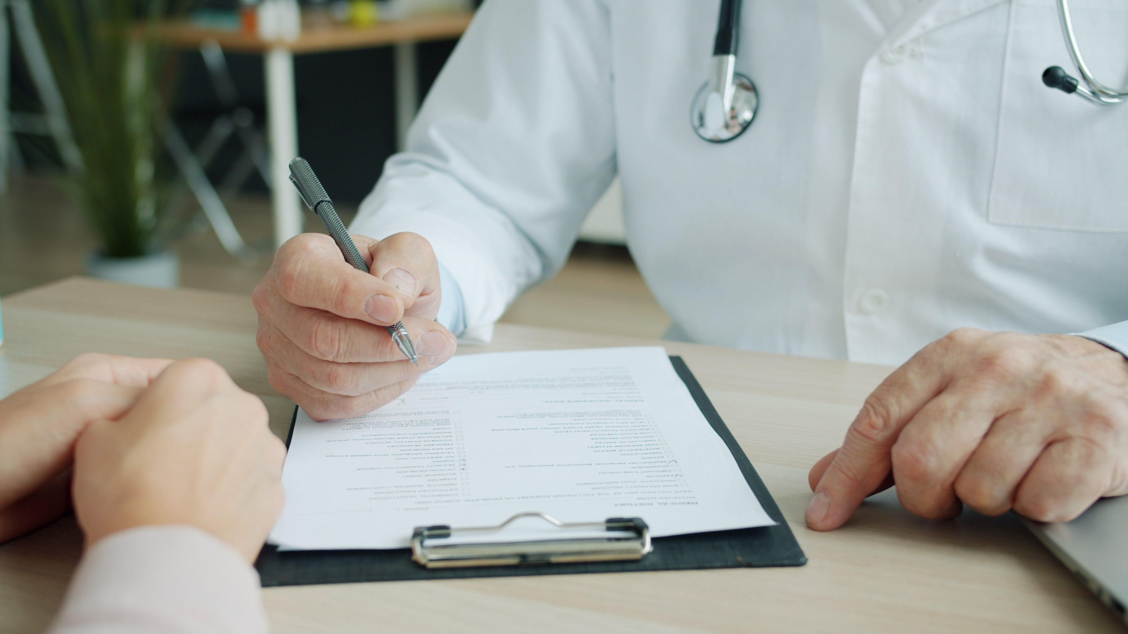 Doctor and patient reviewing medical documents during a consultation about healthcare needs and coverage.